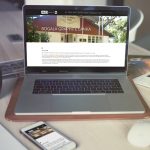 Laptop mit offener Seite der AMG Graphite Website. Daneben auf dem Tisch eine Kaffeetasse, ein Mobiltelefon und eine aufgeschlagene Zeitschrift